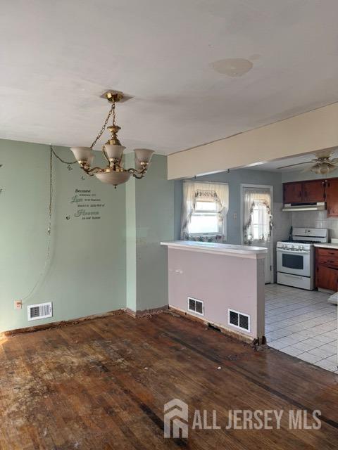 unfurnished dining area featuring a notable chandelier, light wood-style floors, and visible vents