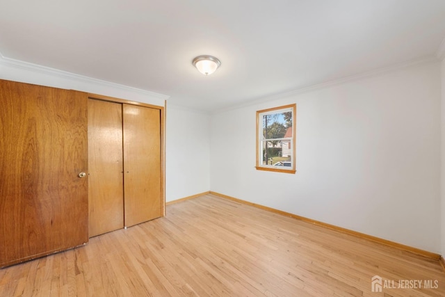 unfurnished bedroom with crown molding, a closet, and light wood-type flooring