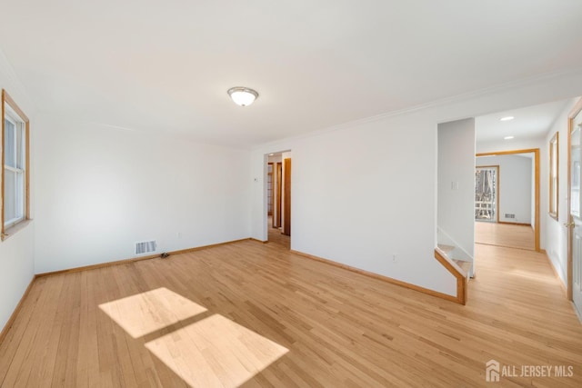 spare room featuring crown molding and light wood-type flooring