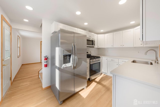 kitchen with white cabinetry, appliances with stainless steel finishes, sink, and light wood-type flooring