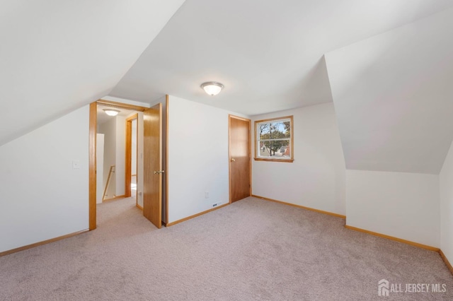 bonus room with lofted ceiling and light carpet