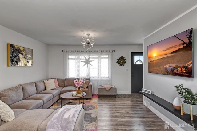 living room featuring dark wood-type flooring, a chandelier, and baseboards