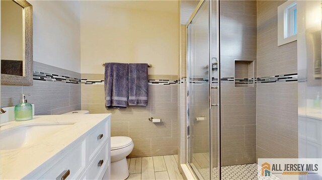 624 Lyman Ave, Woodbridge Proper, NJ 07095 - bathroom with tile walls, vanity, a shower stall, toilet, and wainscoting