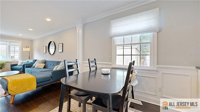 dining area with a decorative wall, dark wood-style floors, a wainscoted wall, and ornamental molding