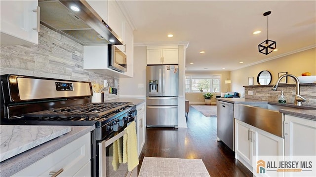 kitchen featuring a sink, ornamental molding, stainless steel appliances, white cabinets, and wall chimney range hood