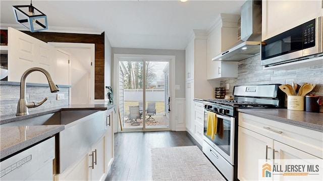 kitchen with dark wood-type flooring, light stone counters, appliances with stainless steel finishes, white cabinetry, and wall chimney exhaust hood