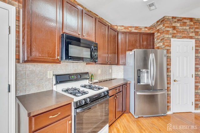 1 Kushnetki Rd, Parlin, NJ 08859 - kitchen featuring black microwave, white gas stove, stainless steel refrigerator with ice dispenser, backsplash, and brick wall