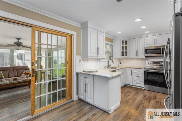 2 Belmar Rd Unit C, Monroe, NJ 08831 - kitchen with appliances with stainless steel finishes, a peninsula, white cabinetry, crown molding, and a sink