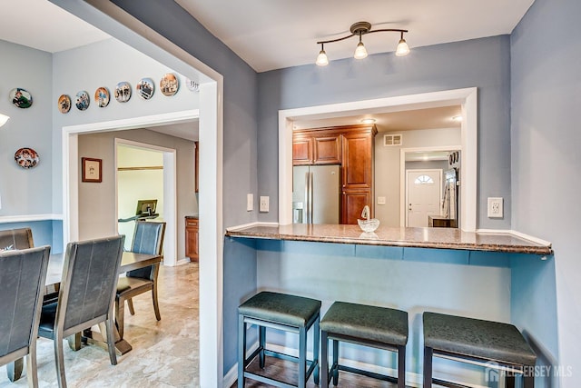 108 Morris Ave, Edison, NJ 08837 - kitchen featuring brown cabinetry, stainless steel fridge with ice dispenser, a breakfast bar, dark stone counters, and a peninsula