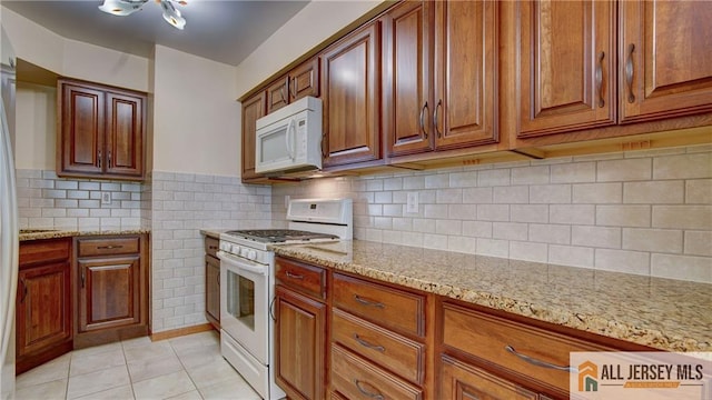 1141 Schmidt Ln, North Brunswick, NJ 08902 - kitchen with white appliances, light tile patterned flooring, light stone counters, and brown cabinetry