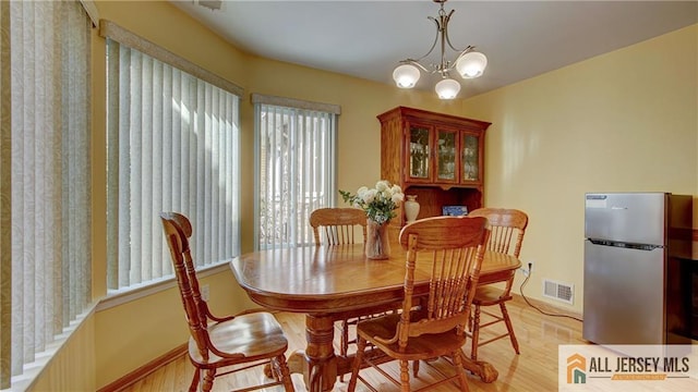 1141 Schmidt Ln, North Brunswick, NJ 08902 - dining room with light wood-type flooring, a chandelier, and baseboards