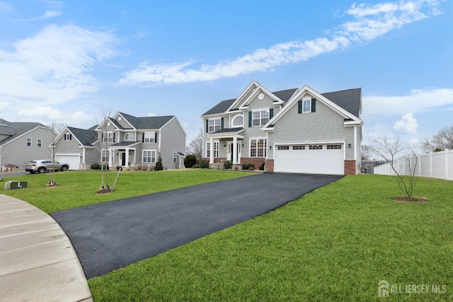 view of front of home with aphalt driveway, brick siding, fence, a residential view, and a front yard