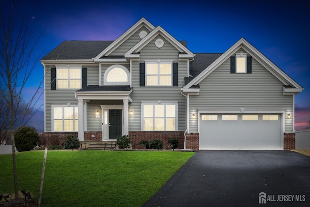 traditional-style home featuring a front yard, aphalt driveway, and brick siding