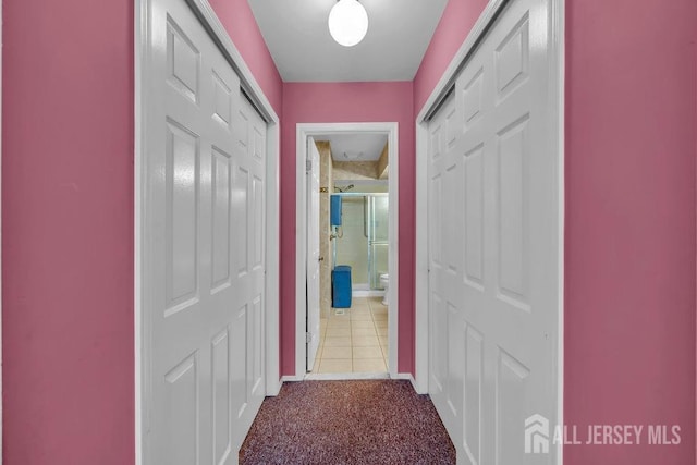 hallway featuring carpet flooring and baseboards