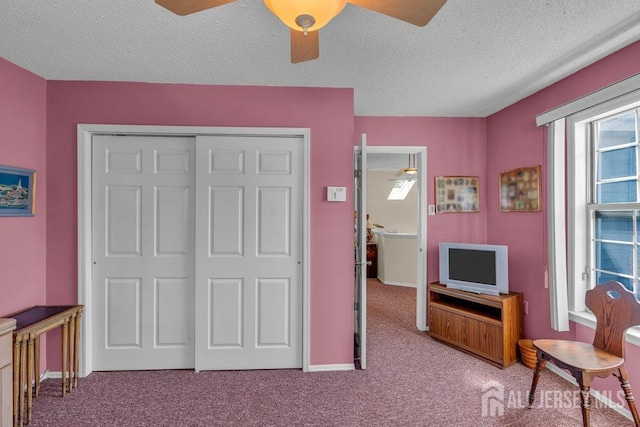 carpeted bedroom featuring baseboards, a ceiling fan, a closet, and a textured ceiling