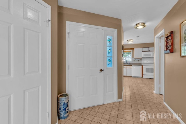 foyer featuring light tile patterned flooring and baseboards