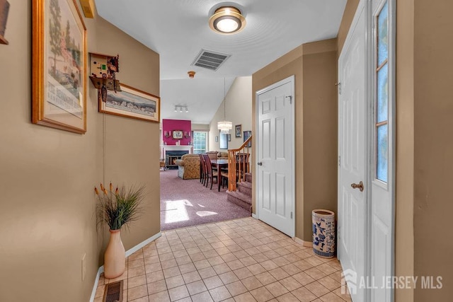 entrance foyer featuring visible vents, baseboards, light tile patterned floors, and light carpet