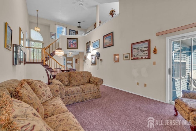 carpeted living room featuring stairway, baseboards, a high ceiling, and a notable chandelier