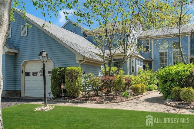 view of property exterior with a garage, roof with shingles, a yard, and driveway