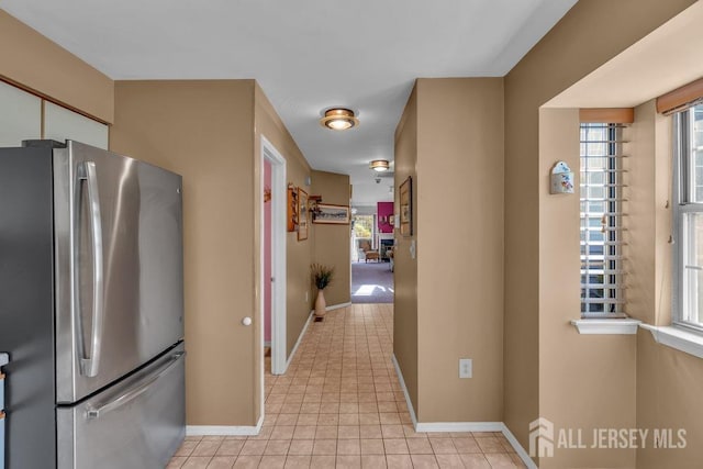 kitchen featuring freestanding refrigerator, white cabinetry, baseboards, and light tile patterned floors