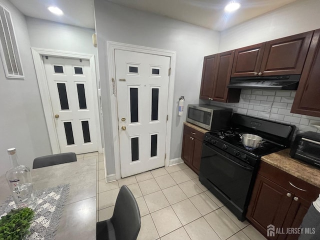 142 Joyce Kilmer Ave, New Brunswick, NJ 08901 - kitchen with black range with gas stovetop, stainless steel microwave, under cabinet range hood, tasteful backsplash, and light tile patterned flooring