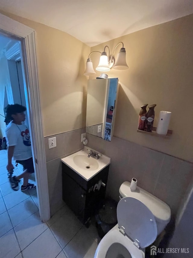 142 Joyce Kilmer Ave, New Brunswick, NJ 08901 - half bath with tile walls, toilet, vanity, tile patterned flooring, and a wainscoted wall