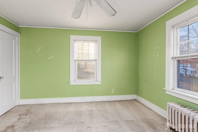 carpeted spare room featuring radiator, crown molding, and ceiling fan