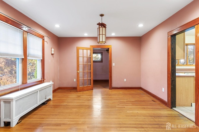 unfurnished room with radiator heating unit, light hardwood / wood-style floors, and french doors