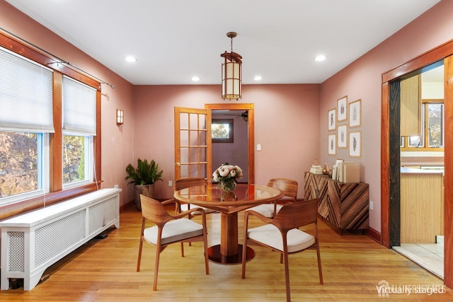 dining room with radiator heating unit, french doors, and light hardwood / wood-style flooring