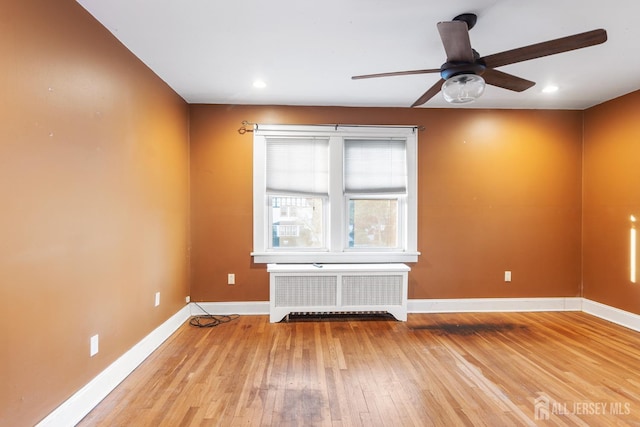 unfurnished room featuring ceiling fan, radiator, and light hardwood / wood-style flooring