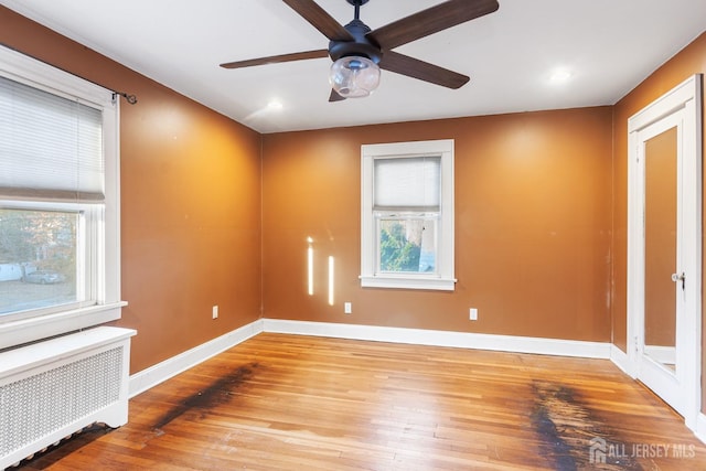 spare room with ceiling fan, radiator heating unit, and light wood-type flooring