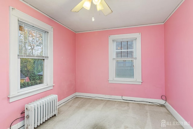 carpeted empty room with radiator, ceiling fan, and ornamental molding