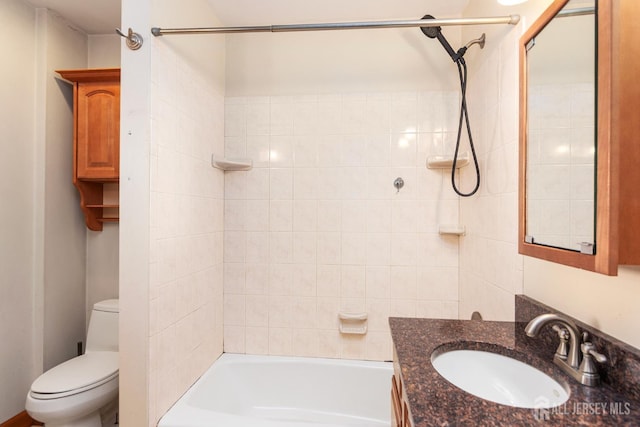 full bathroom featuring vanity, tiled shower / bath, and toilet