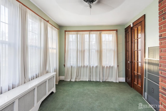 interior space featuring ceiling fan, radiator heating unit, and dark colored carpet