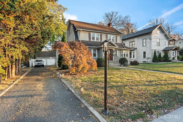 view of front facade with a garage, an outbuilding, and a front yard