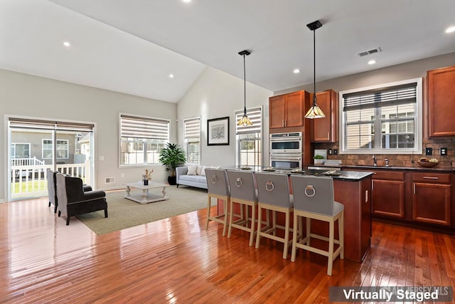 kitchen featuring a center island, decorative backsplash, dark hardwood / wood-style flooring, decorative light fixtures, and vaulted ceiling