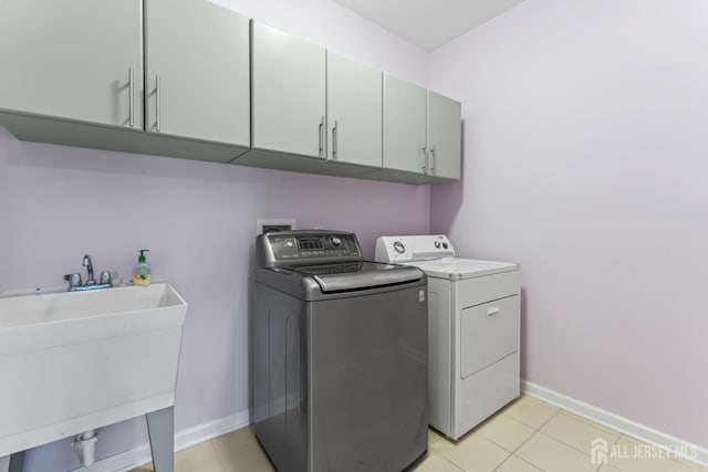 laundry area with sink, light tile patterned floors, cabinets, and washing machine and clothes dryer