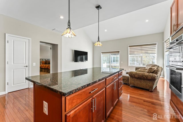 kitchen with pendant lighting, a center island, light hardwood / wood-style flooring, and dark stone countertops