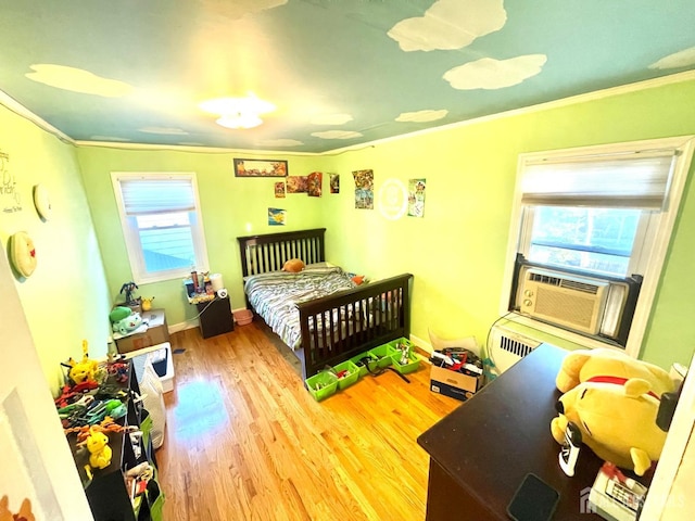 bedroom with cooling unit, ornamental molding, and light wood-type flooring