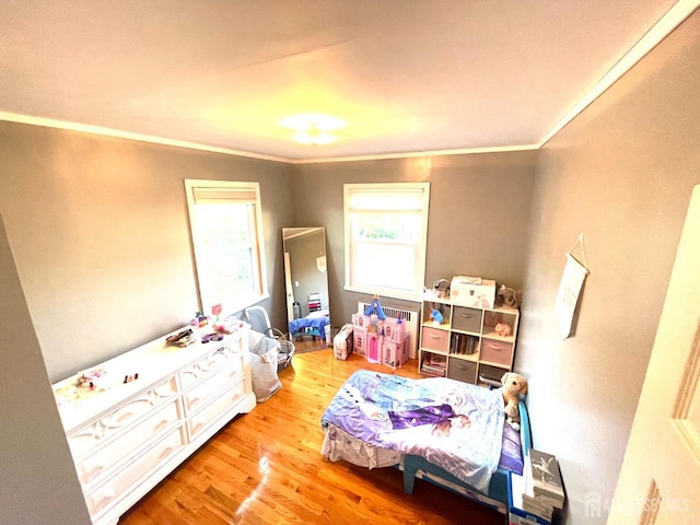 bedroom featuring ornamental molding and light wood-type flooring