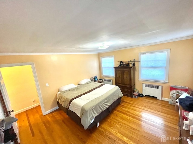 bedroom with a wall unit AC, radiator heating unit, wood-type flooring, and ornamental molding