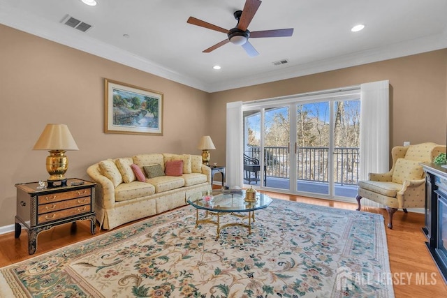 living room featuring ornamental molding, visible vents, and light wood finished floors