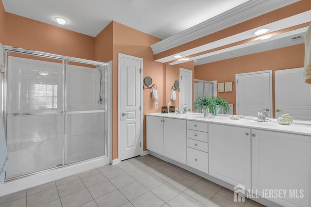 bathroom featuring a stall shower, tile patterned floors, a sink, and double vanity