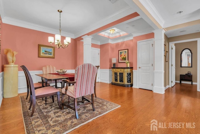 dining space with light wood-style floors, wainscoting, decorative columns, and crown molding