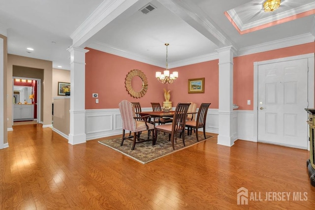 dining area featuring wood finished floors, visible vents, and ornate columns