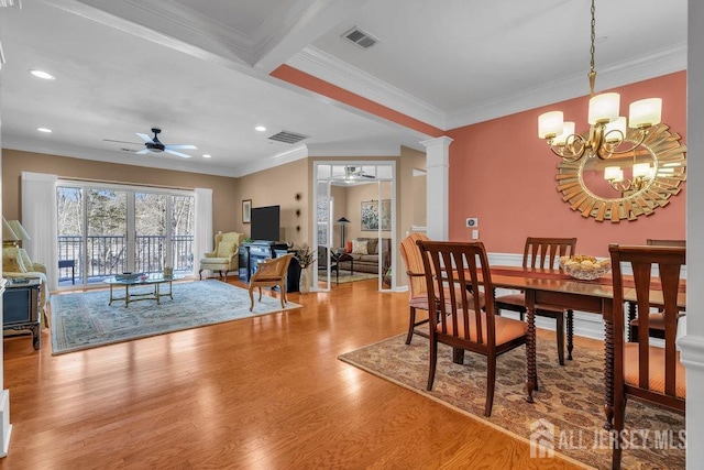 dining space with ceiling fan with notable chandelier, wood finished floors, visible vents, and ornate columns