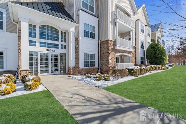 exterior space featuring french doors, stone siding, metal roof, a standing seam roof, and a yard