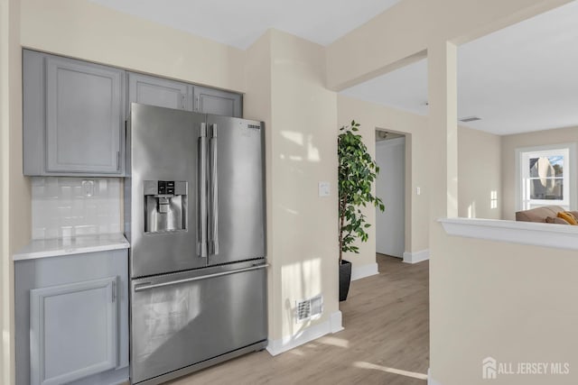 kitchen featuring visible vents, light countertops, gray cabinets, light wood-style flooring, and stainless steel fridge