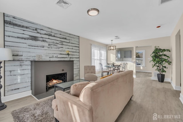 living area featuring visible vents, baseboards, a lit fireplace, and wood finished floors