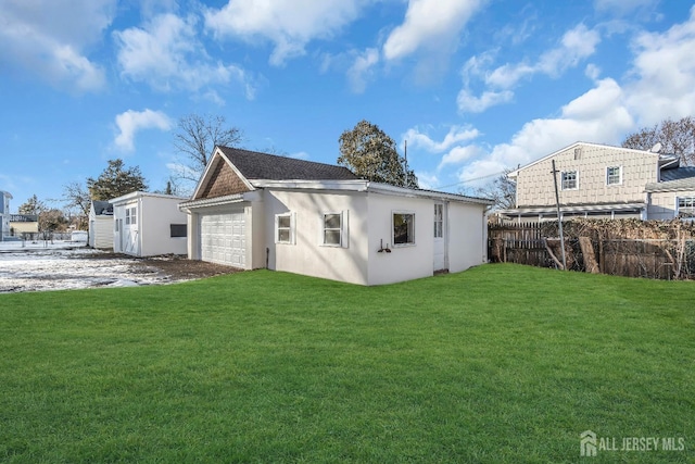 back of property featuring an outbuilding, fence, a yard, stucco siding, and a garage